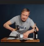 Ein Mann sitzt an einem Tisch mit einer Flasche Wein und einem Glas